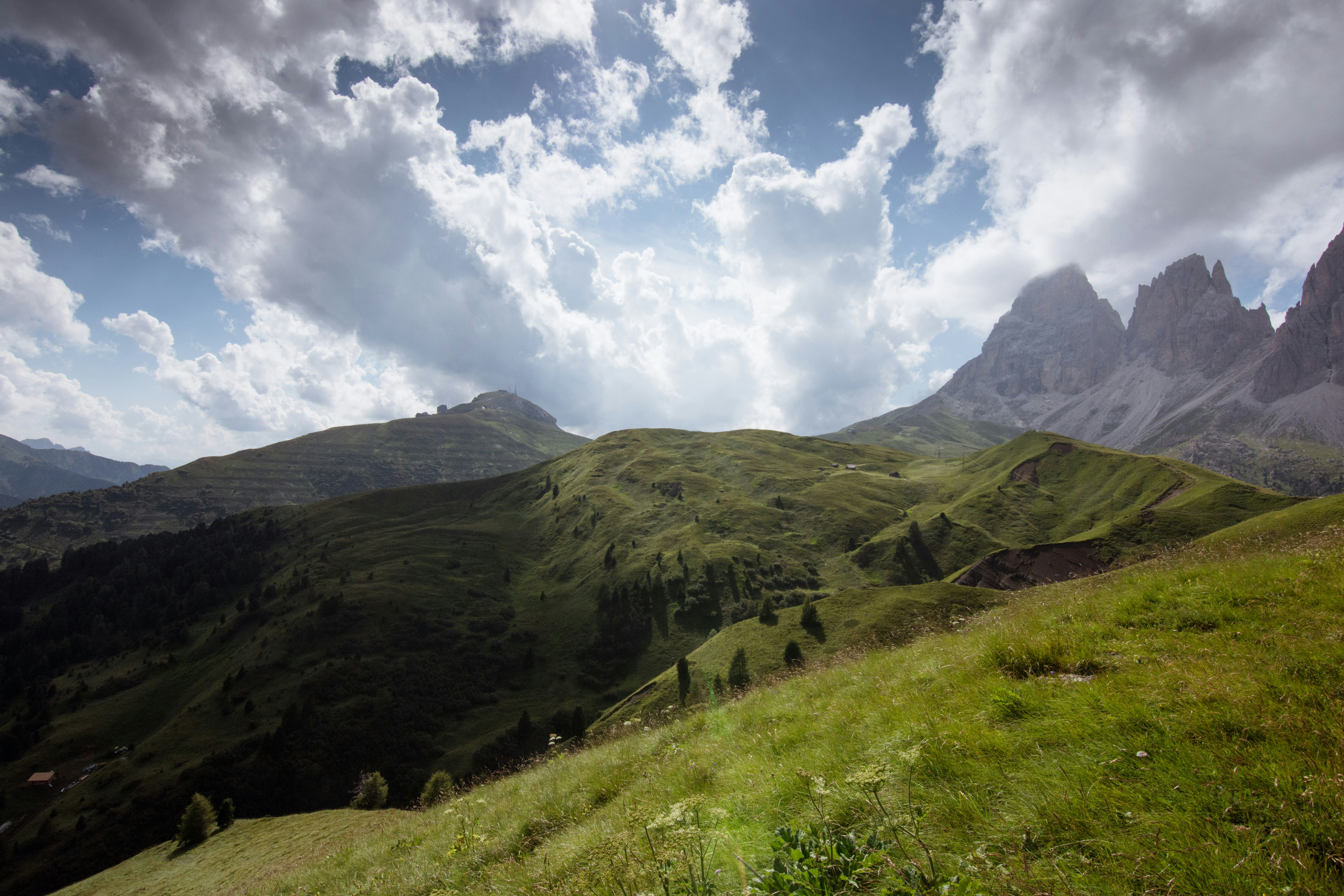 green grass field and mountains under white clouds and blue sky during daytime